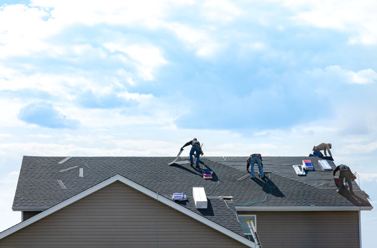 Four-person Minneapolis roofing crew installing new shingles on a suburban home