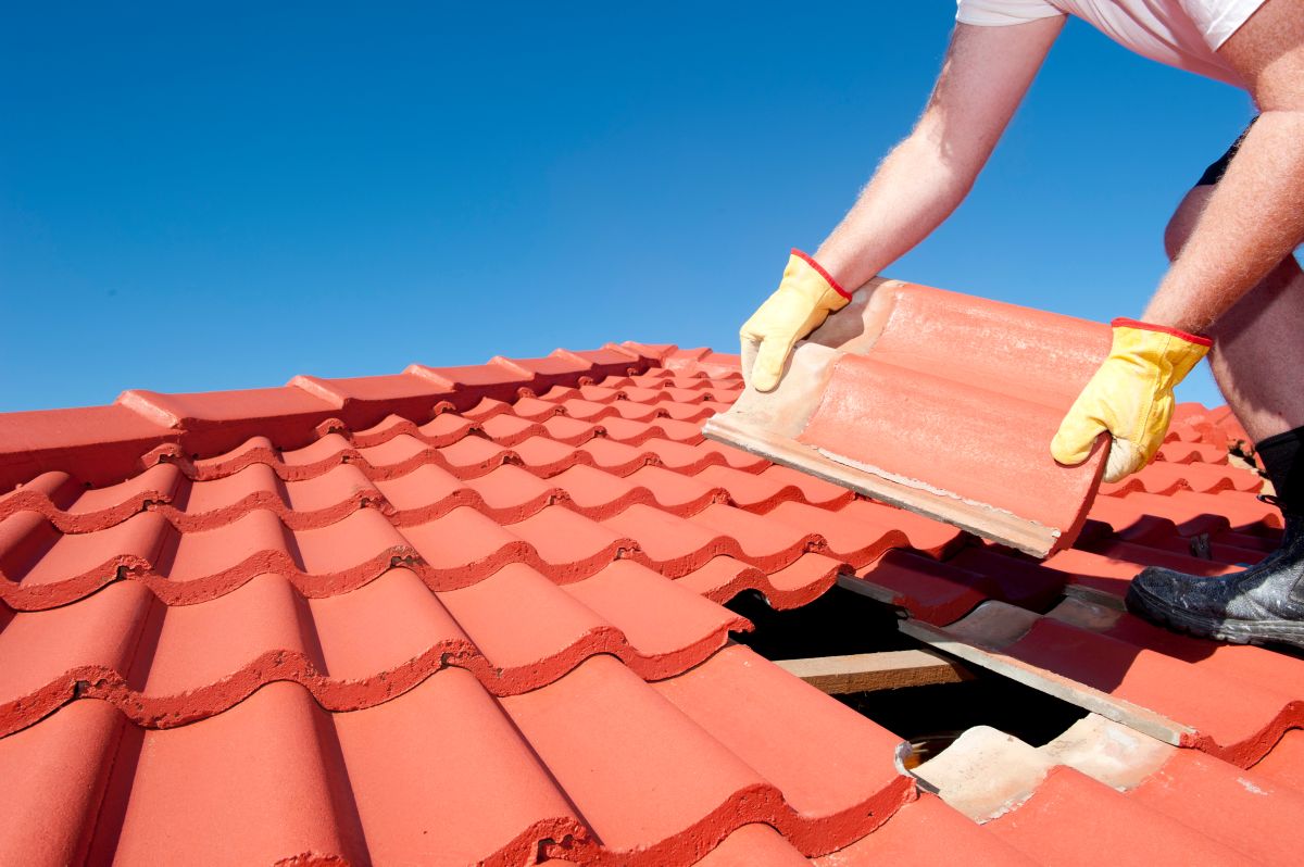 A technician working at roof eave height — the baseline safety scenario for any DIY gutter installation consideration