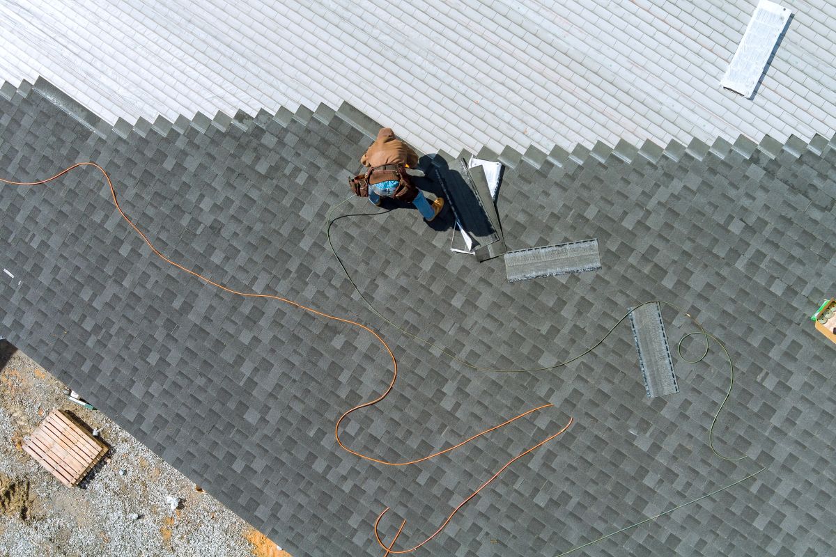 Certified roofer nailing architectural asphalt shingles during a Minneapolis roof replacement