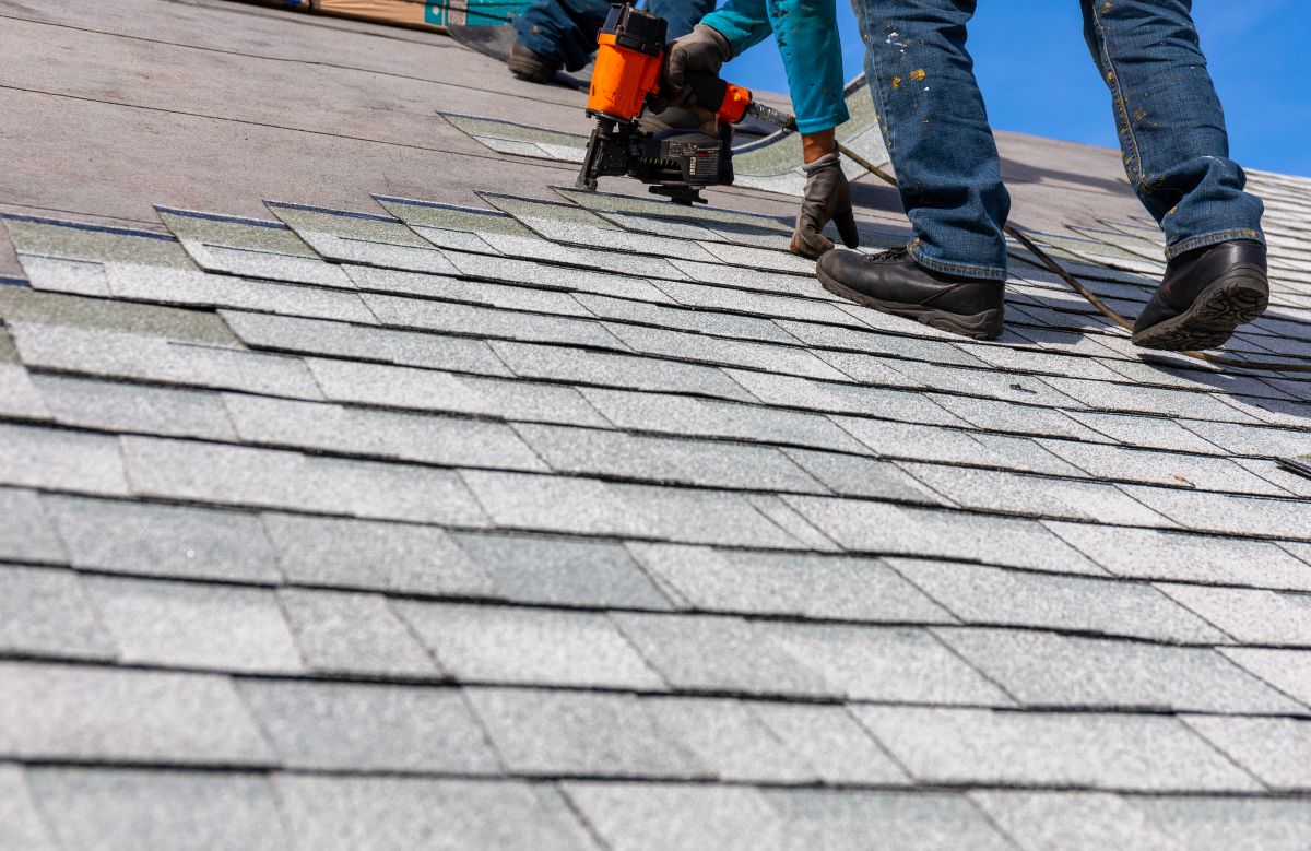 Roofer installing asphalt shingles with a pneumatic nail gun on a Minneapolis home