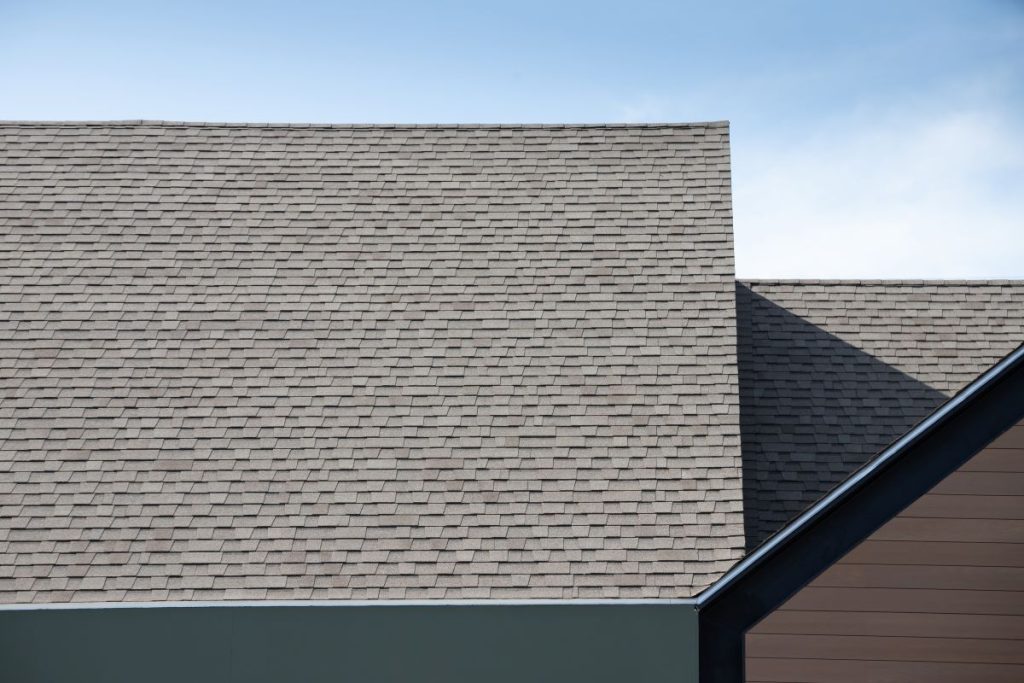 Roof shingles on top of the house against blue sky. dark asphalt tiles on the roof background, Shoreview