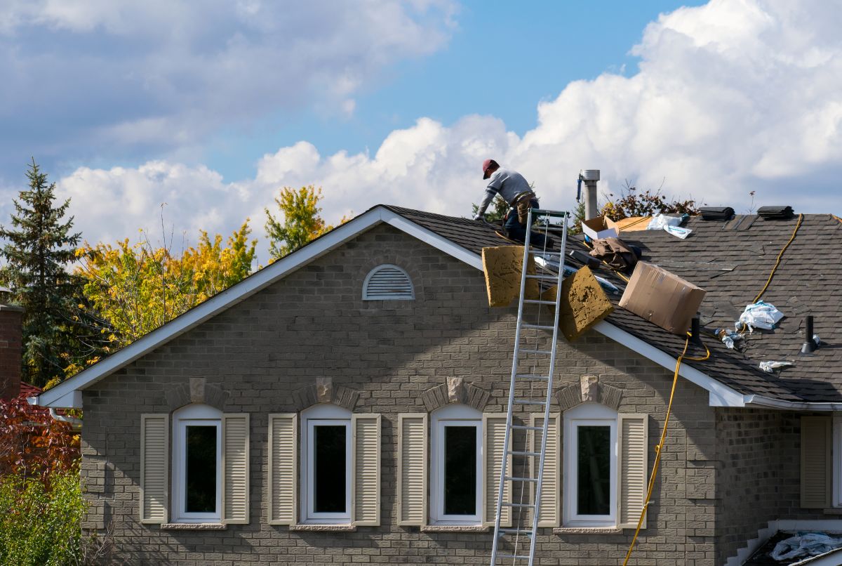 Roofing worker on the roof of a house adding a new layer of asphalt shingles, Shoreview